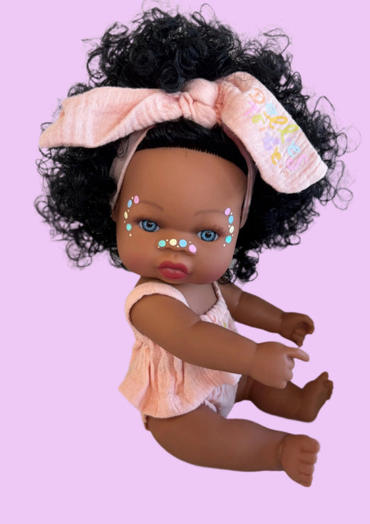 Doll with curly hair and a headband on a pink background
